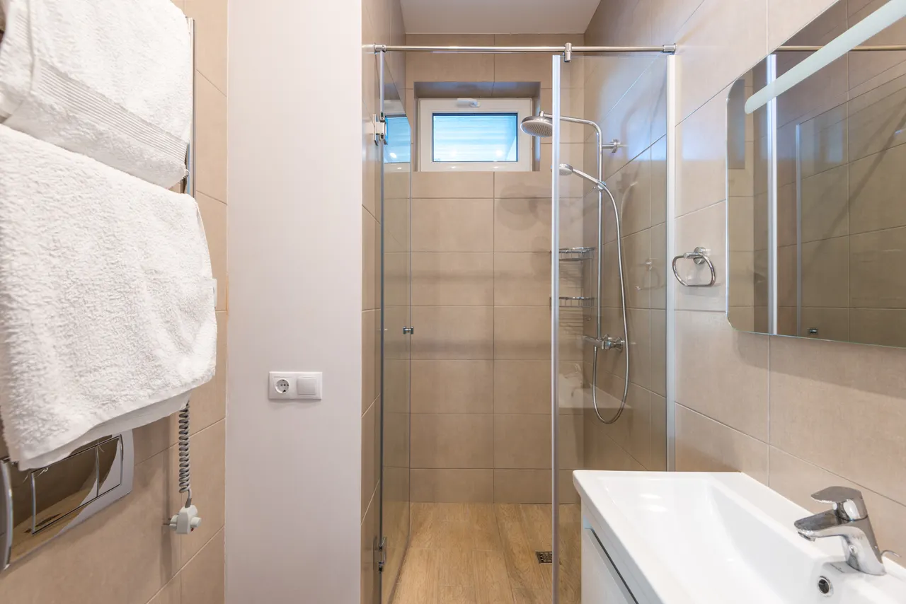 A tiled bathroom with a glass shower enclosure and white sink