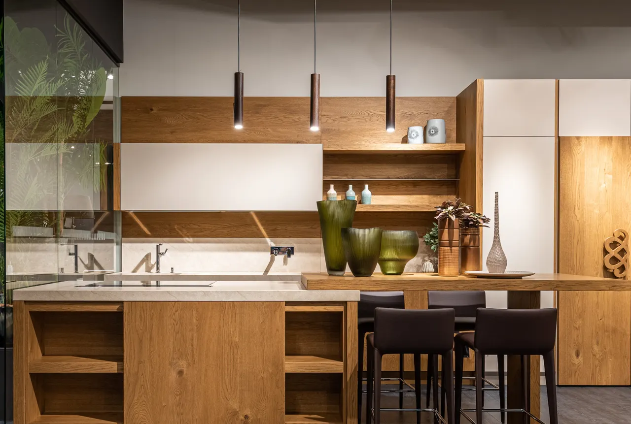 A kitchen interior with wooden cabinetry, pendant lights and a counter with stools