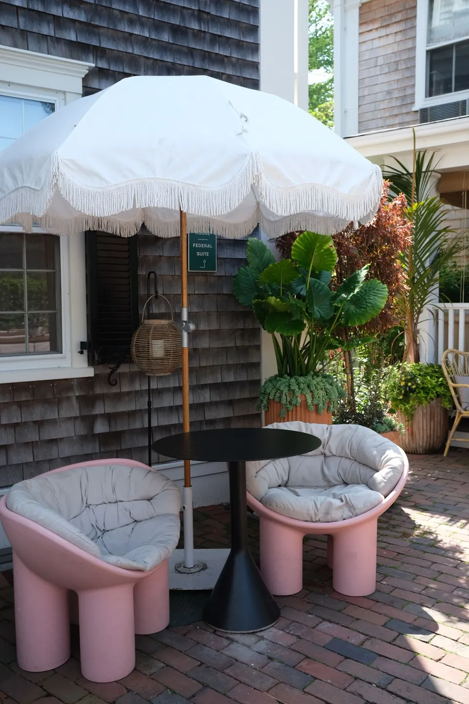 Patio seating and garden beside a shingled building in Nantucket