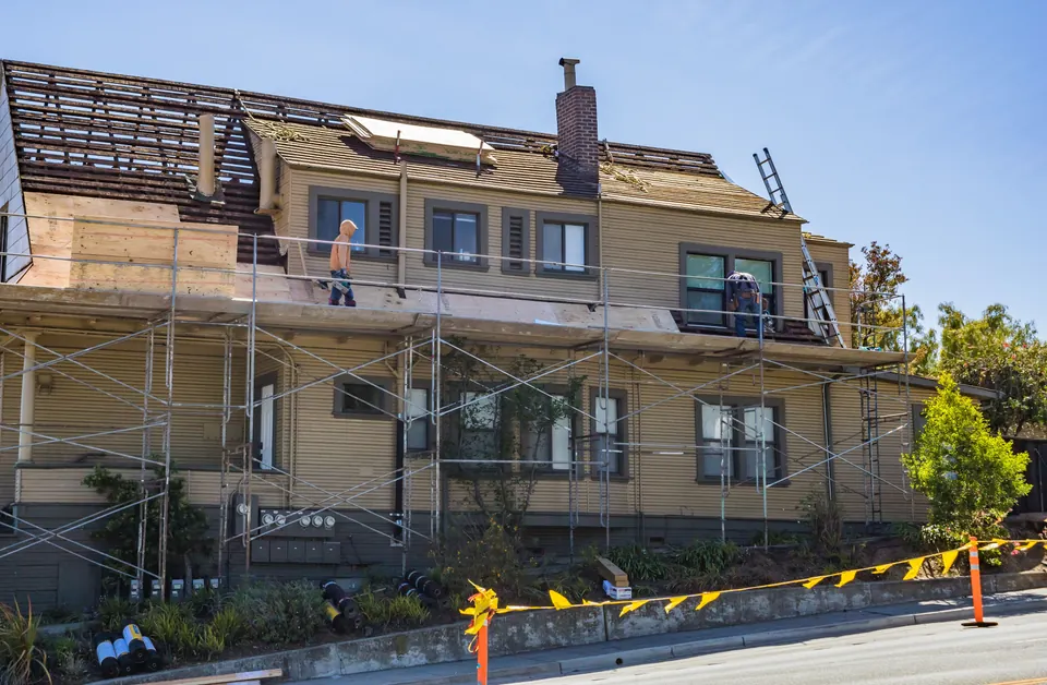 A house undergoing roof work with scaffolding and construction materials